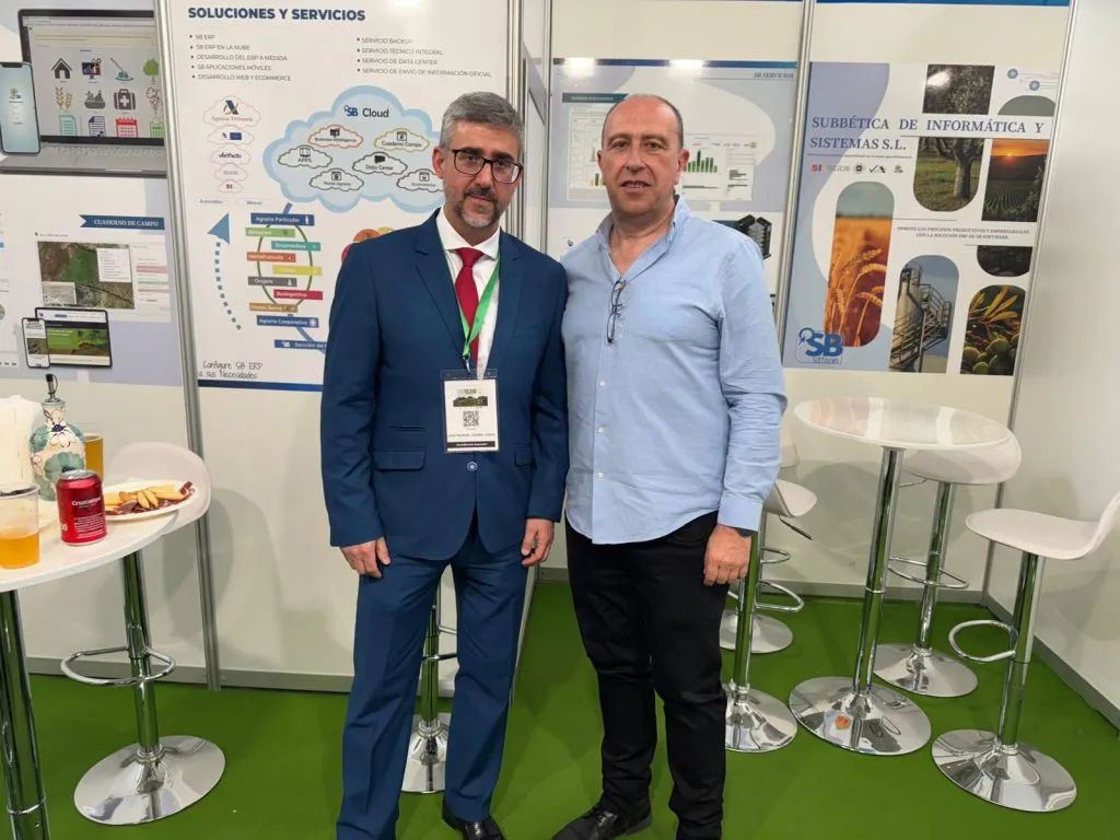 Dos hombres posan en el stand de SB Software, ante los paneles de soluciones y servicios y de SB Cloud