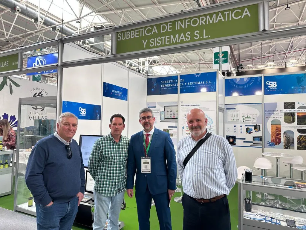 Cuatro hombres posan a la entrada del stand, bajo el rótulo verde de Subbética de Informática y Sistemas