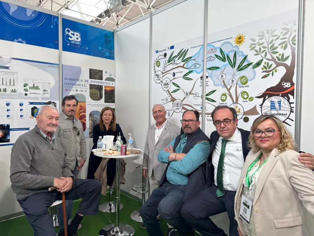 Siete personas posan en el stand ante el gran panel de un olivo con los módulos de SB Almazara